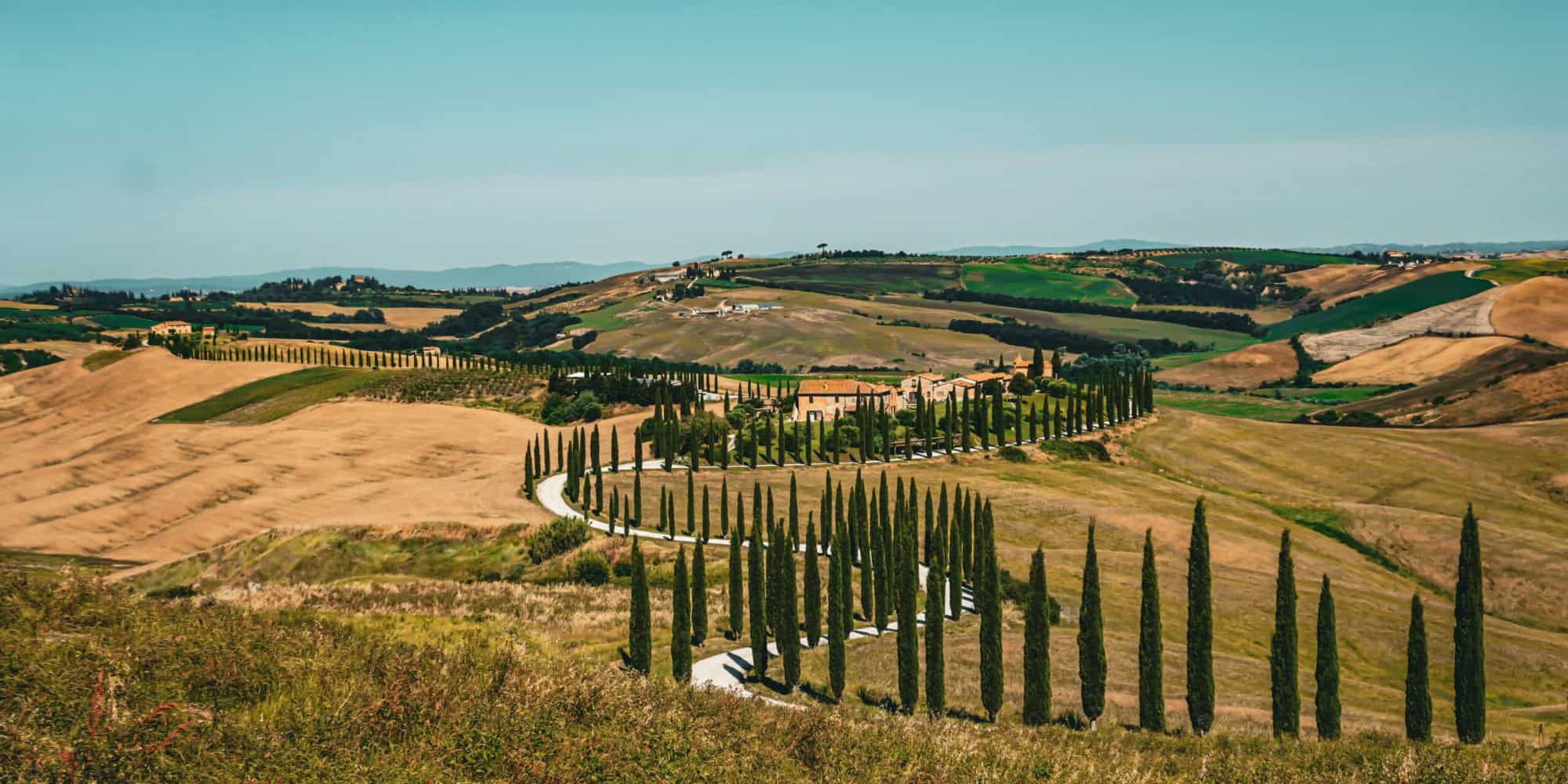 Rolling Tuscan hills with cypress trees under a clear blue sky